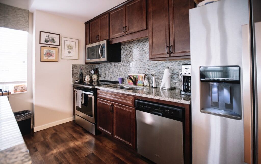 Interior image of a resident's kitchen with rich wooden cabinets and updated appliances.