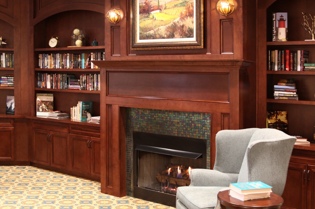 Interior image of The Summit of Citrus Hills sitting room/library with a warm fireplace and wood panelling.